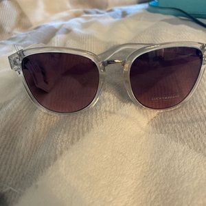 NWT Lucky Sunglasses with clear rim and dark purple/taupe lens.